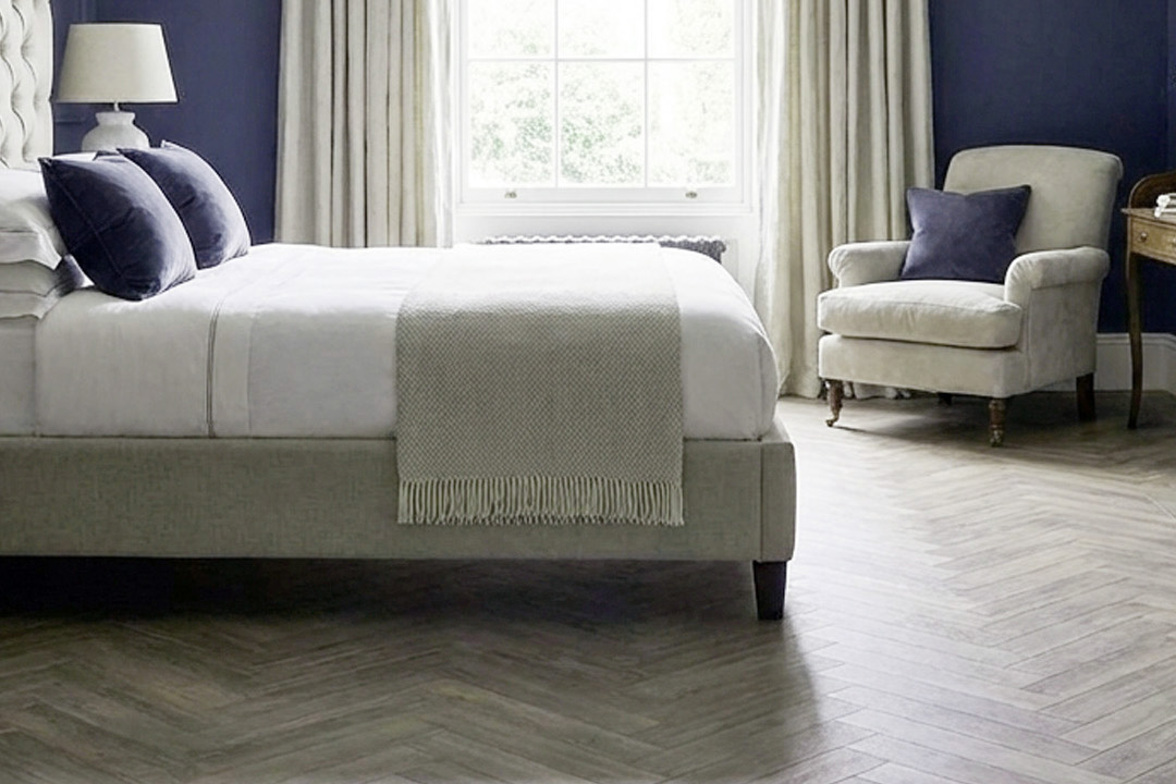 blue bedroom with blue painted walls and herringbone wood flooring